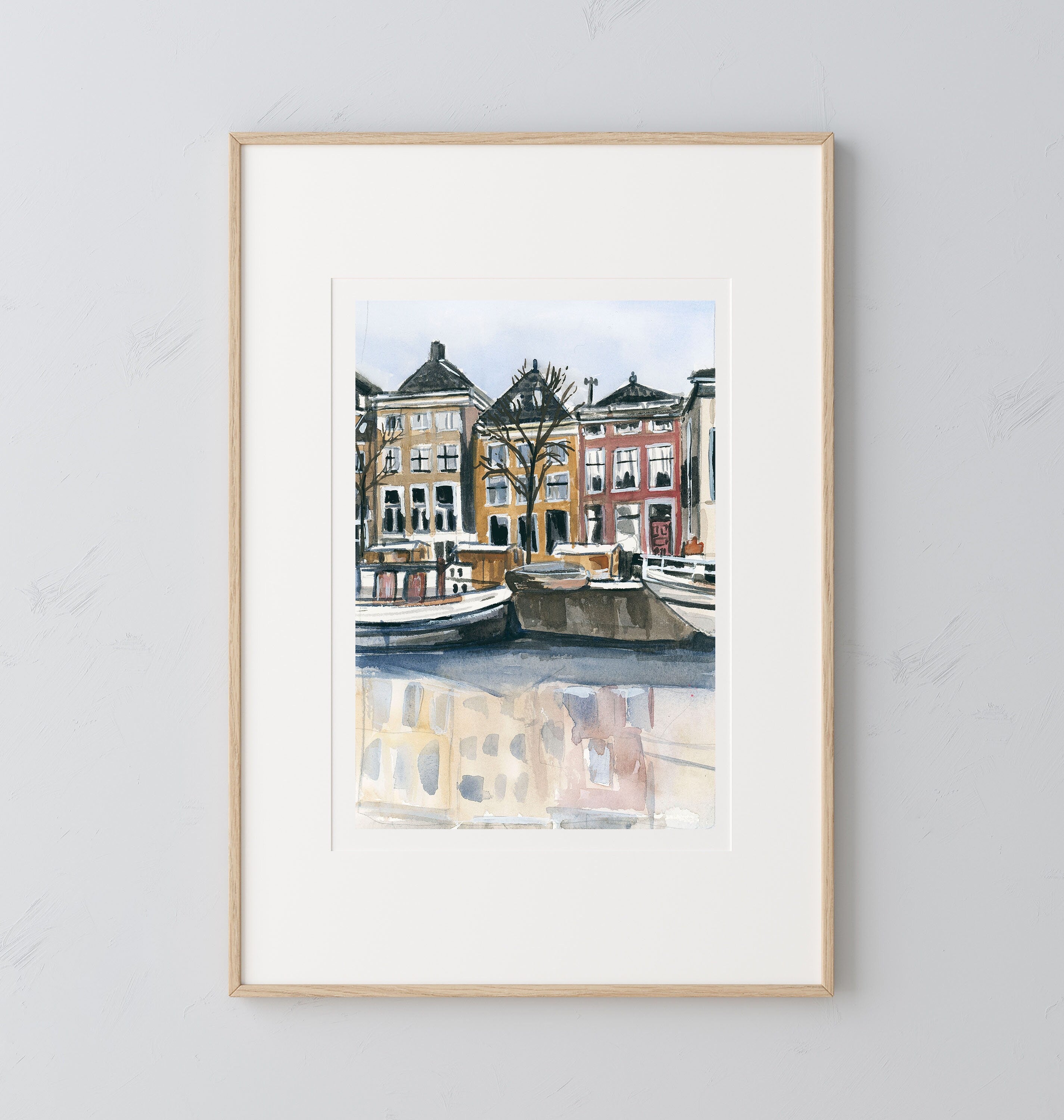 Amsterdam canal print of painting by Medjool Studio. Print of original gouache painting with brown, yellow and red building features behind small boats in the water from the Amsterdam canal.
