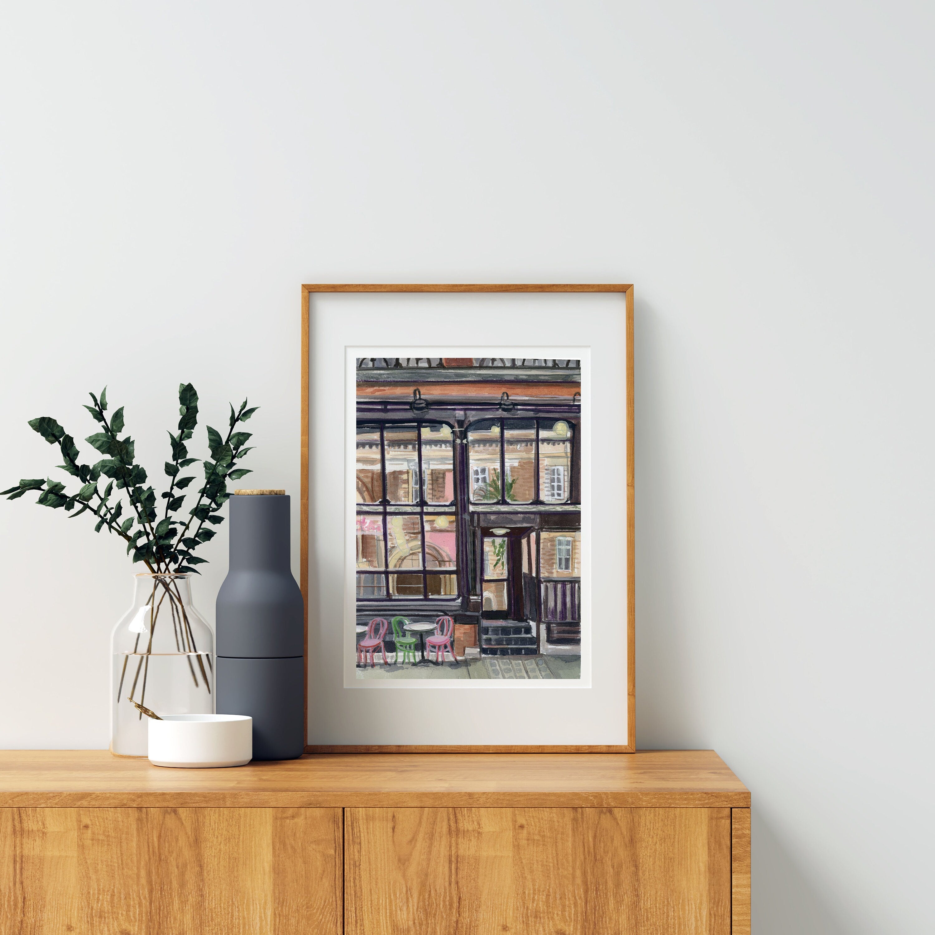 New York city coffee shop print of painting by Medjool Studio. Print of original gouache painting of a New York City cafe. This piece of art transports you to the bustling streets of the Big Apple, where the aroma of freshly brewed coffee and the warmth of community fill the air.