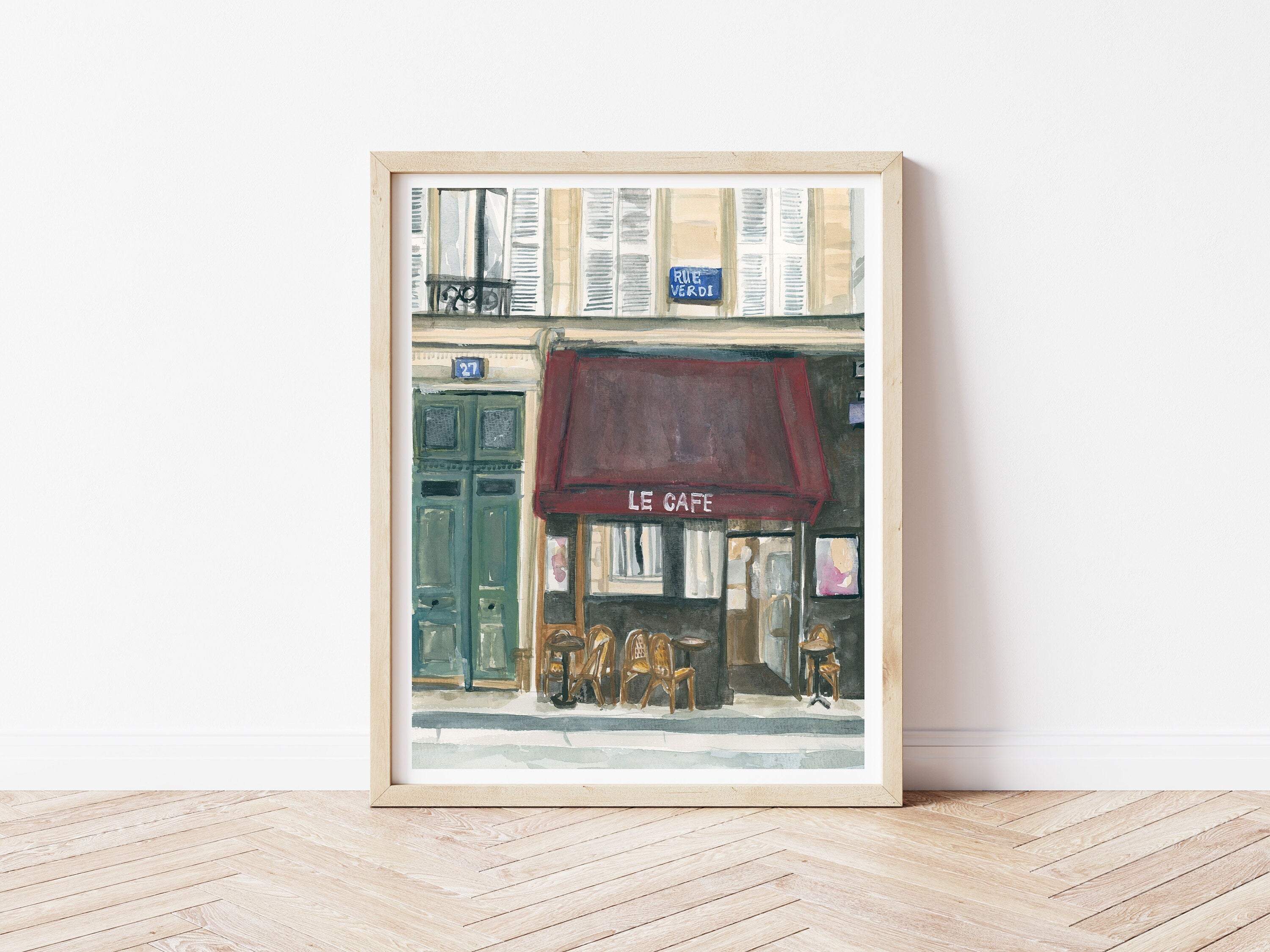 Paris cafe print of painting by Medjool Studio. Print of original gouache painting of the front of a small cafe in Paris, France featuring a burgundy awning, small tables and chairs out front.