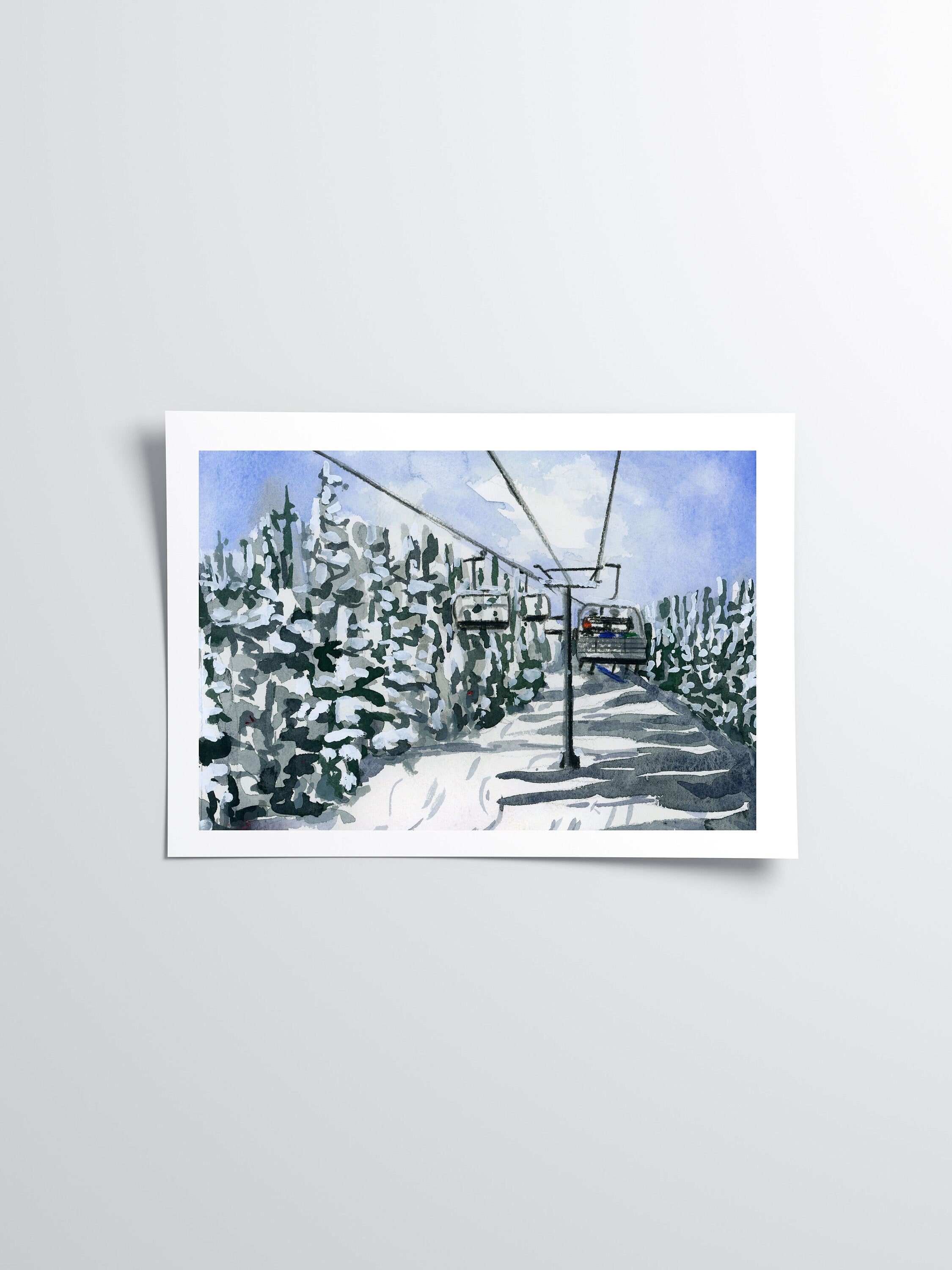 Winter ski lift and forest print of painting by Medjool Studio. Print of an original gouache painting capturing the serene beauty of a ski lift through a row of trees covered in a layer of snow.